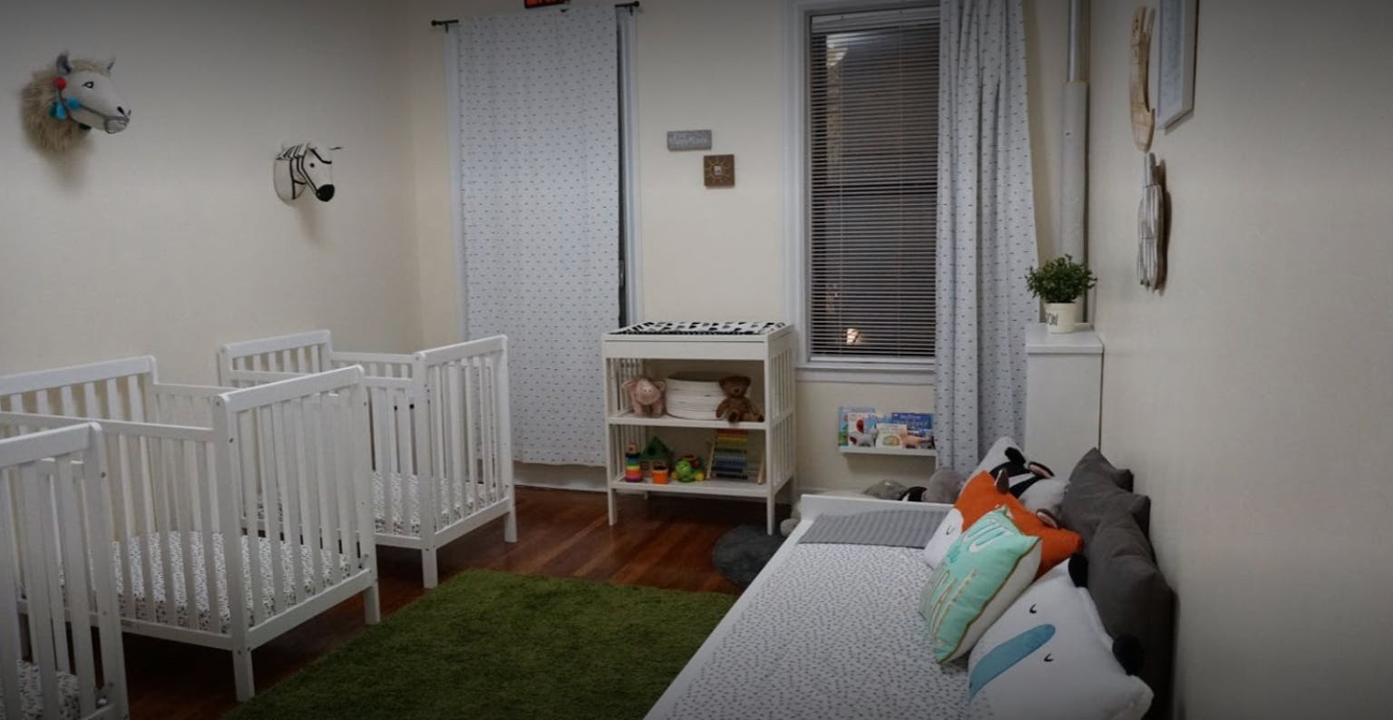 Nursery room with multiple cribs and a changing table