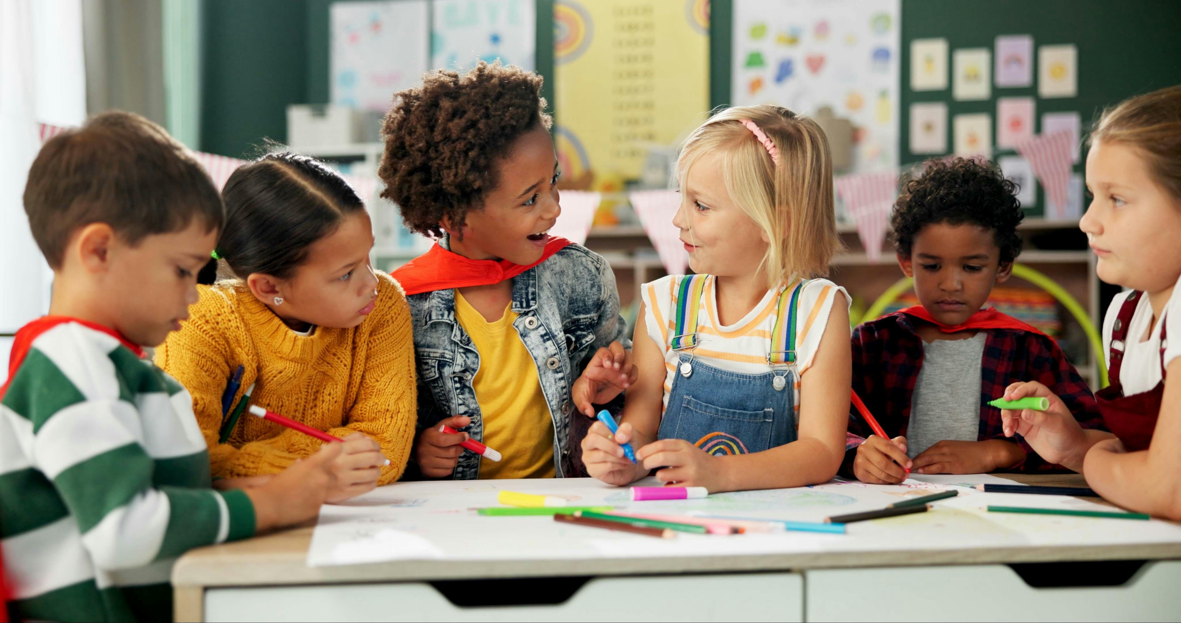 Children drawing and coloring together at a table in a classroom