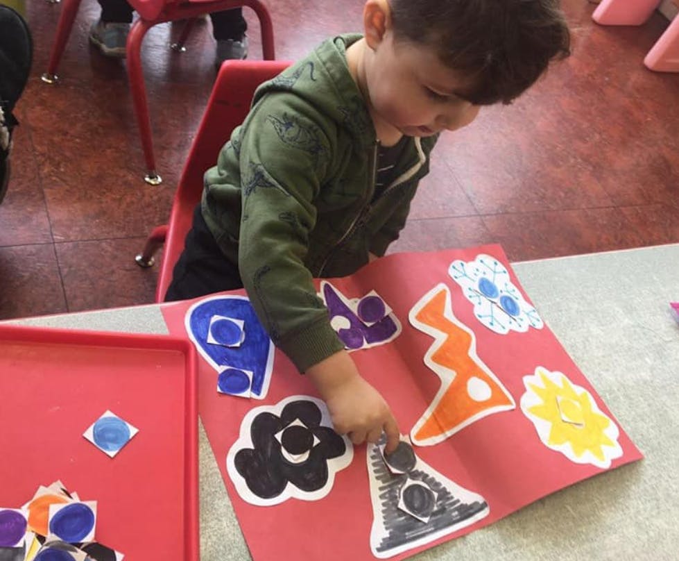 Child doing an art activity with cutouts on red paper