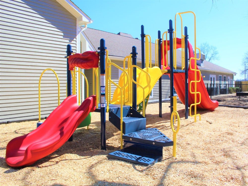 A red and yellow playground with slides on wood chips