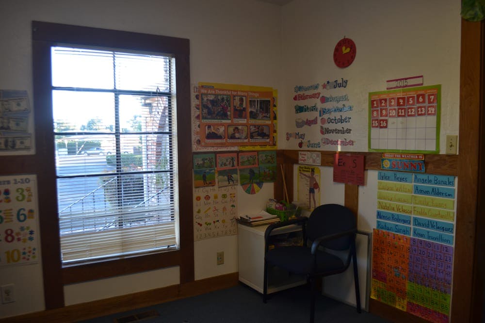 Classroom corner with window, desk, chair, and educational posters on walls
