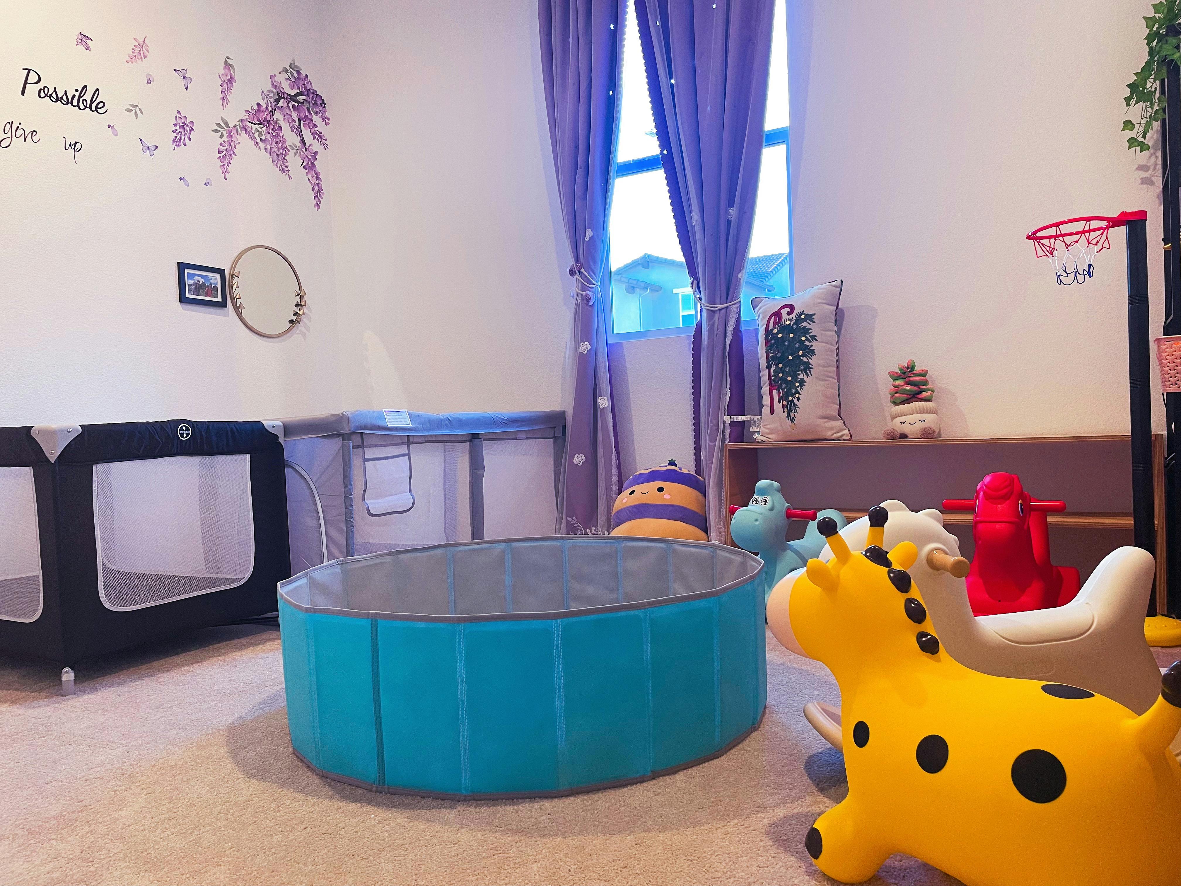 Playroom with a portable playpen, ball pit, and toy animals on carpet