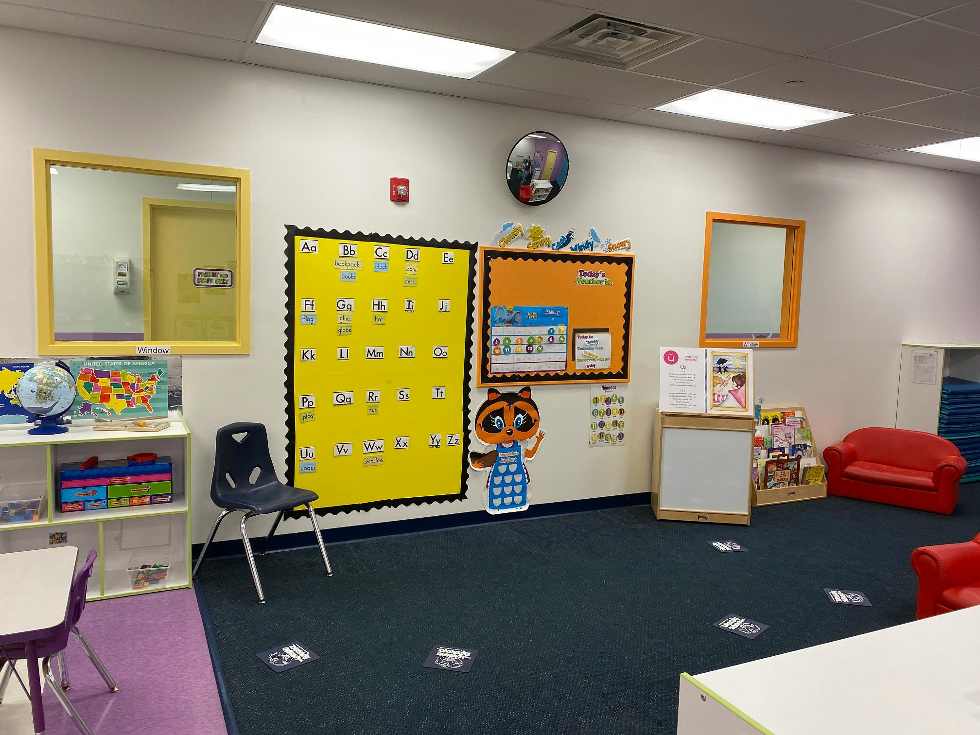 Empty classroom with bulletin boards, small chairs, and red couches