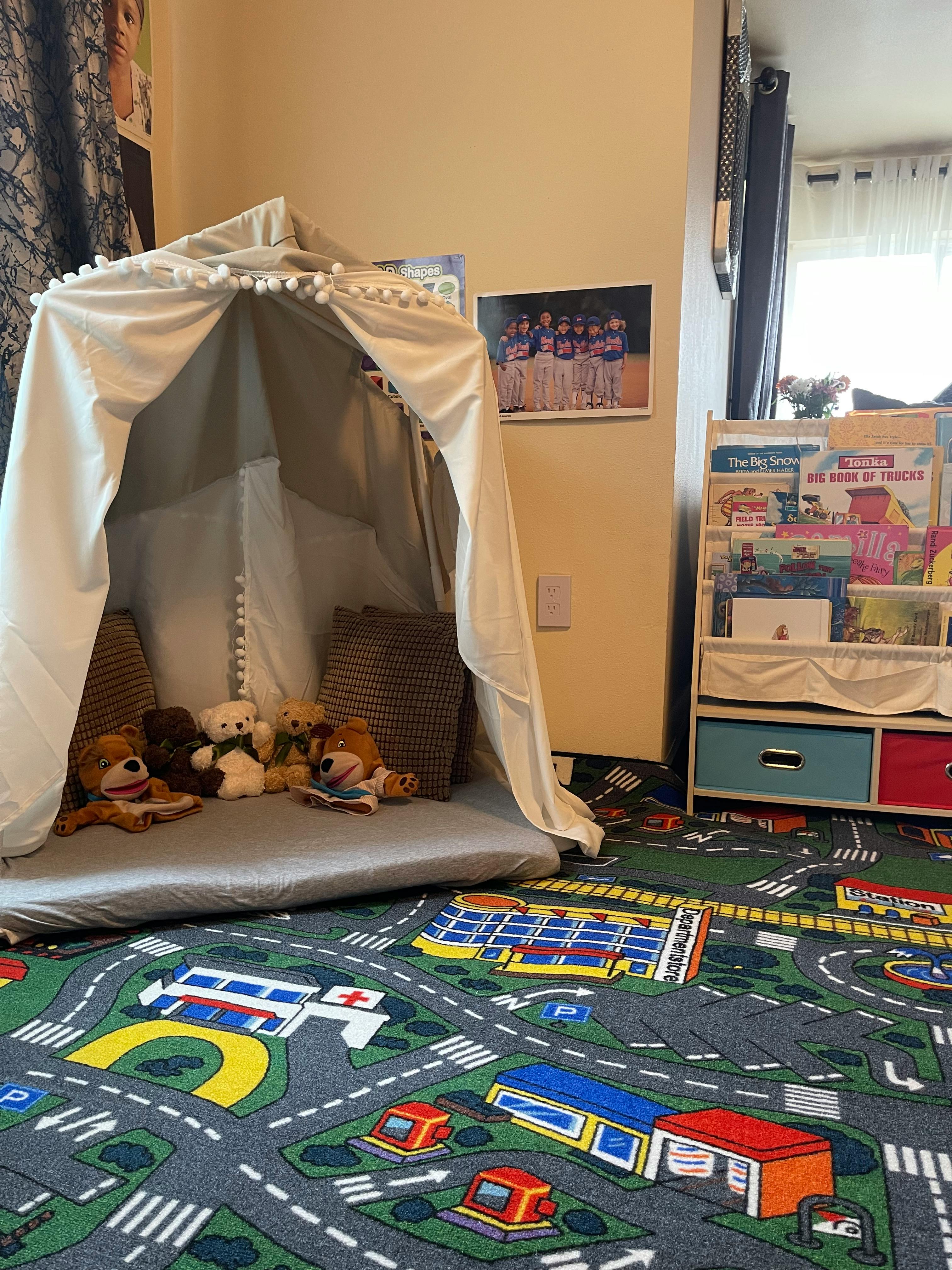 Play tent with stuffed animals and a road map rug in a child's room