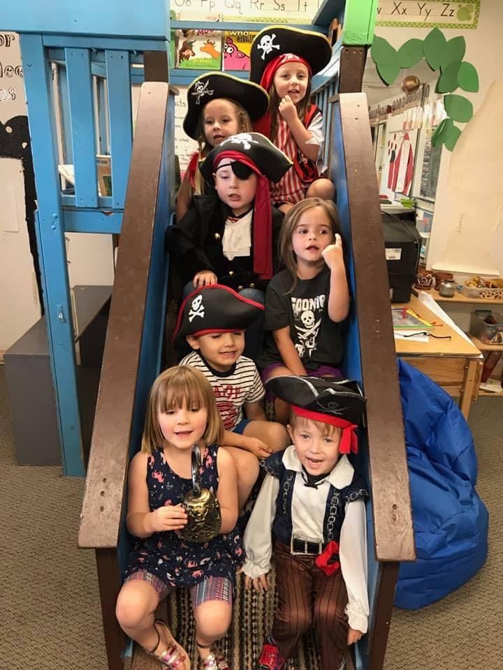 Children in pirate costumes sitting on a play structure