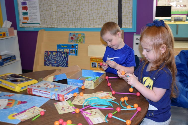 Two children playing with building toys at a table