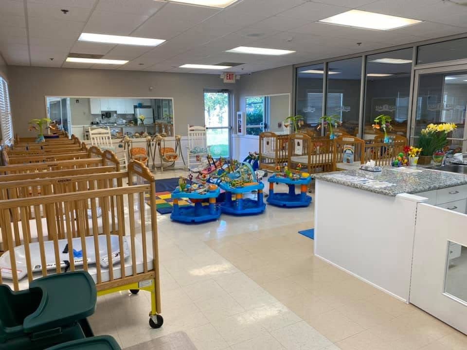 Daycare room with multiple cribs and infant activity centers