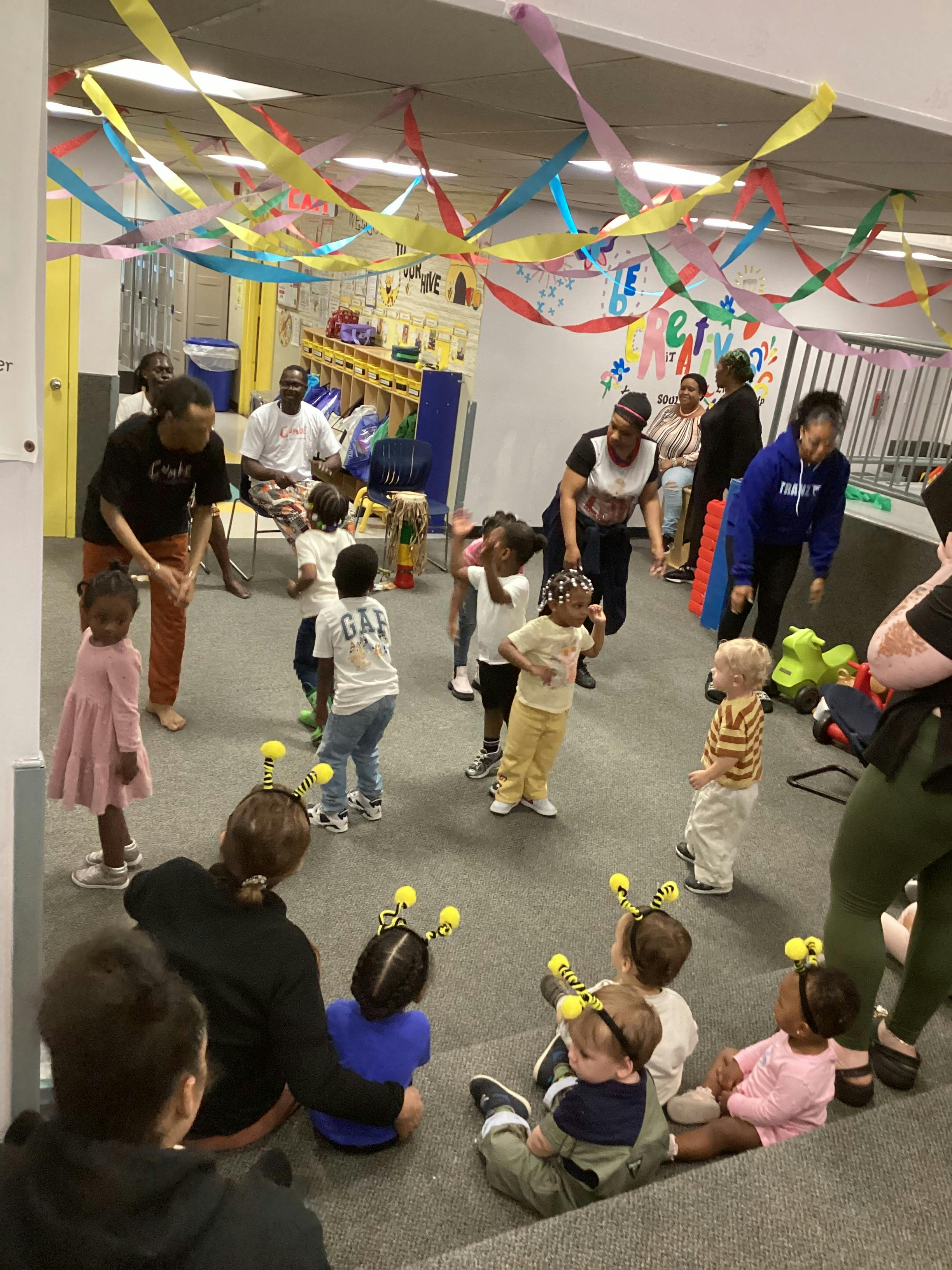 Adults and children dancing in a room decorated with streamers
