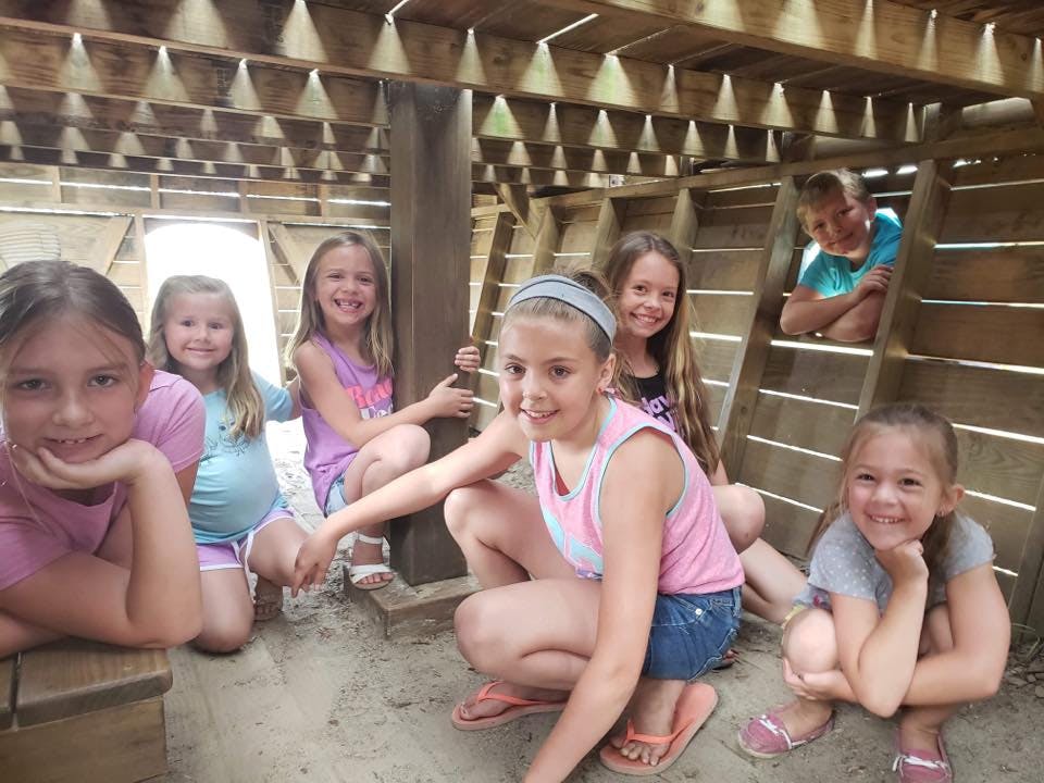 Group of children smiling in a wooden structure