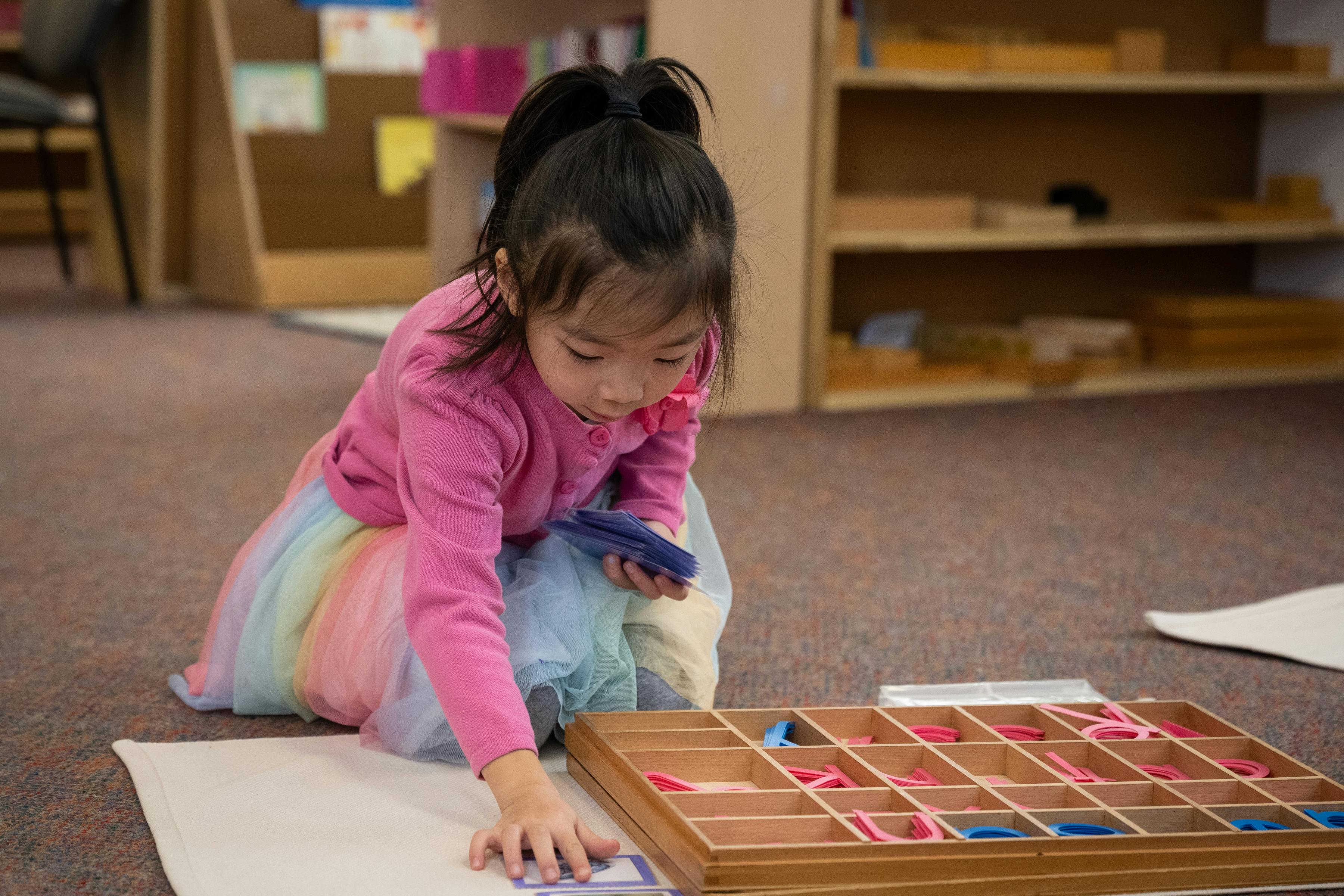 Child playing with a wooden sorting tray in a classroom