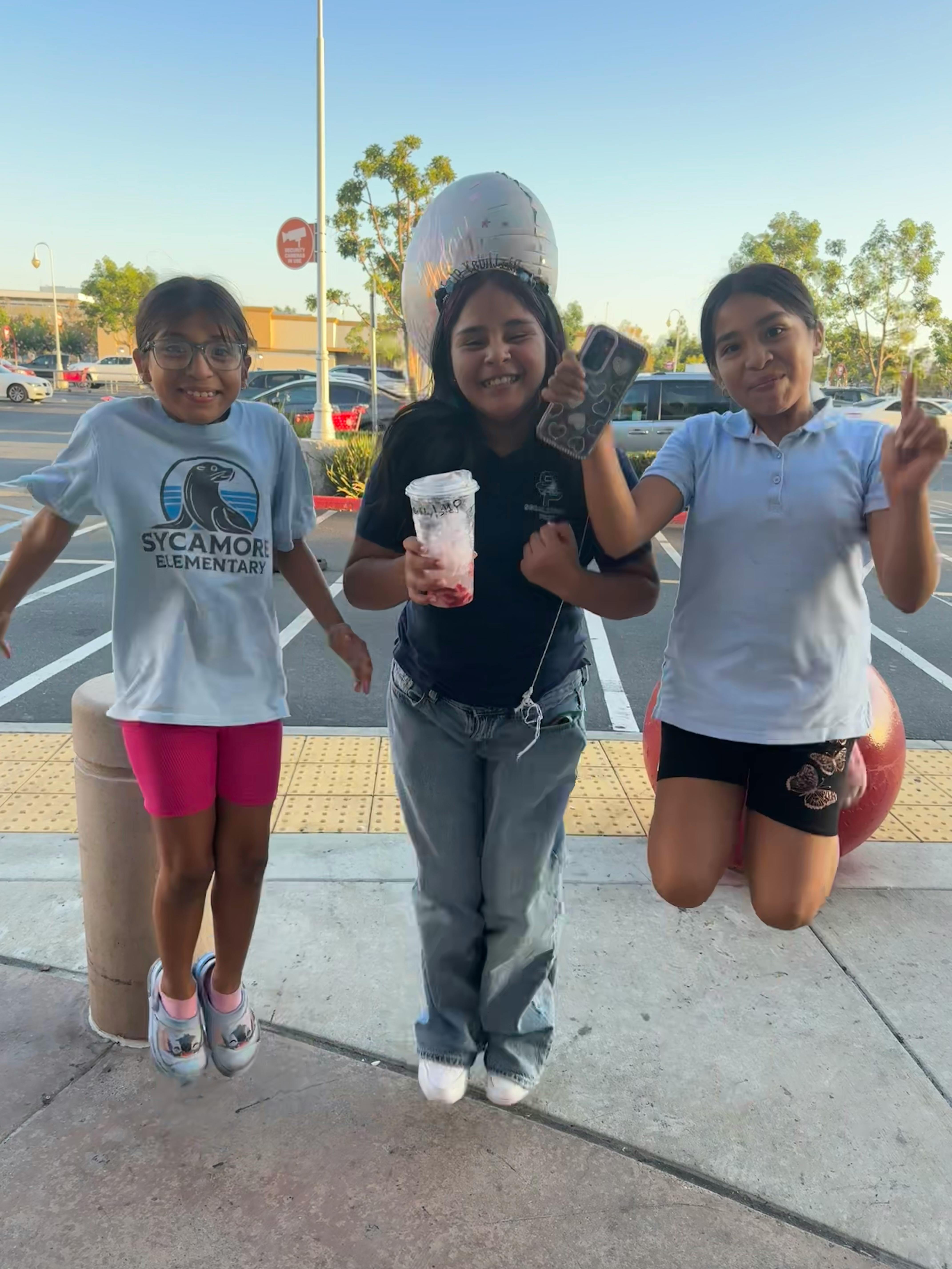 Three children jumping in a parking lot