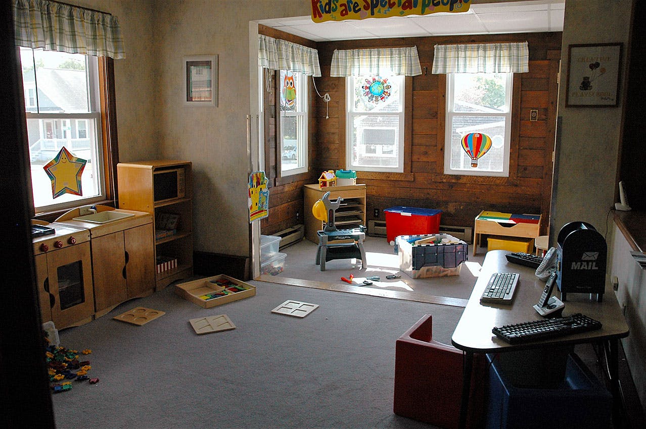 Playroom with toy kitchen, small tables, and windows with decorations