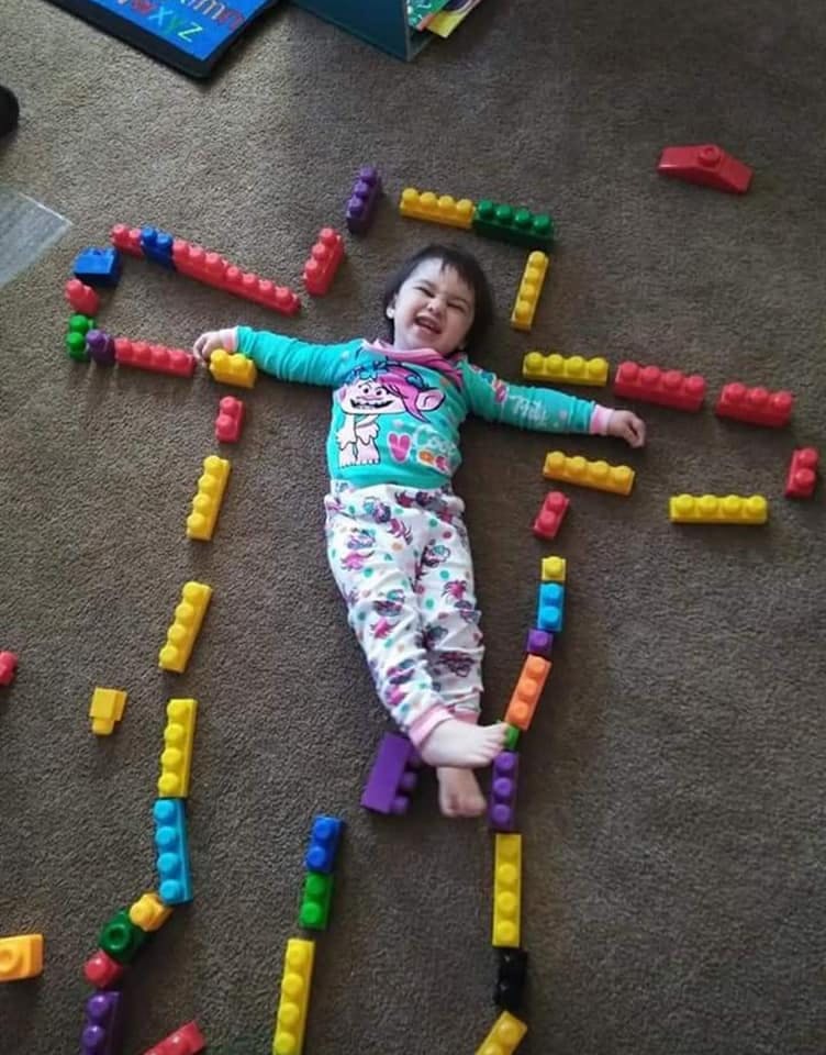 Child lying on floor surrounded by colorful building blocks