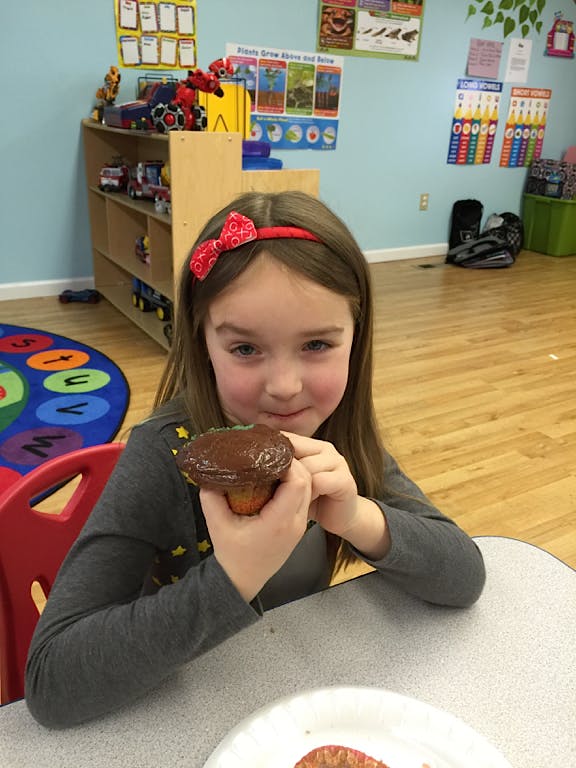 Child holding a cupcake with chocolate frosting