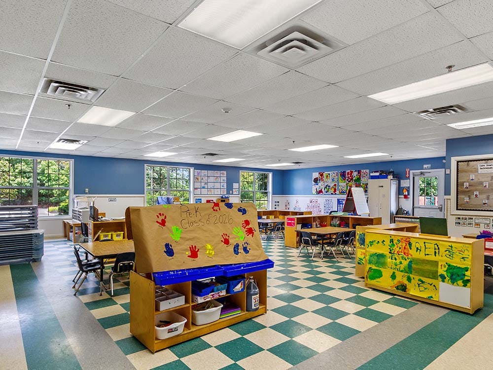Empty classroom with tables, chairs, and colorful artwork on the walls
