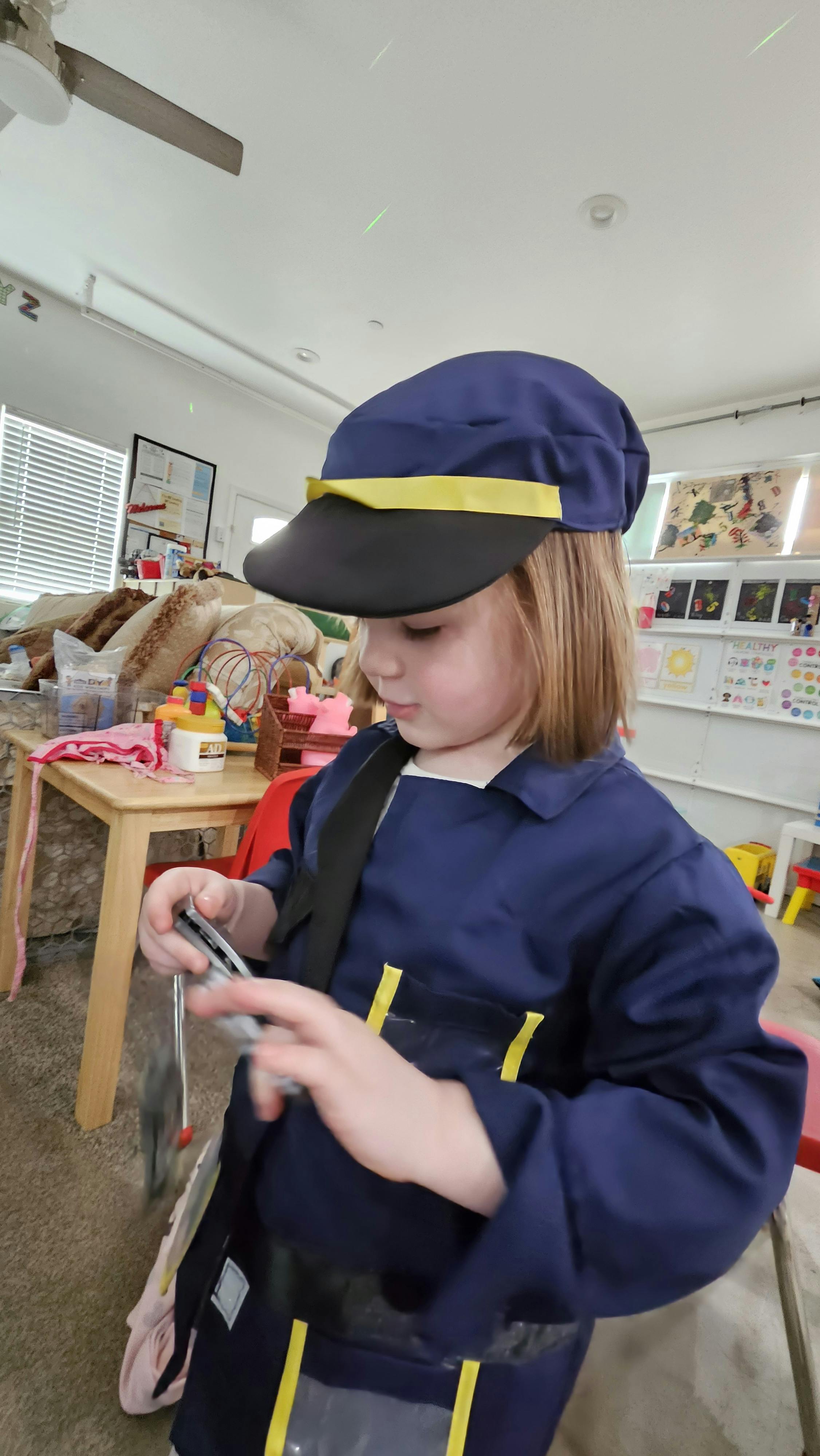 Child in a blue uniform and hat holding a small object