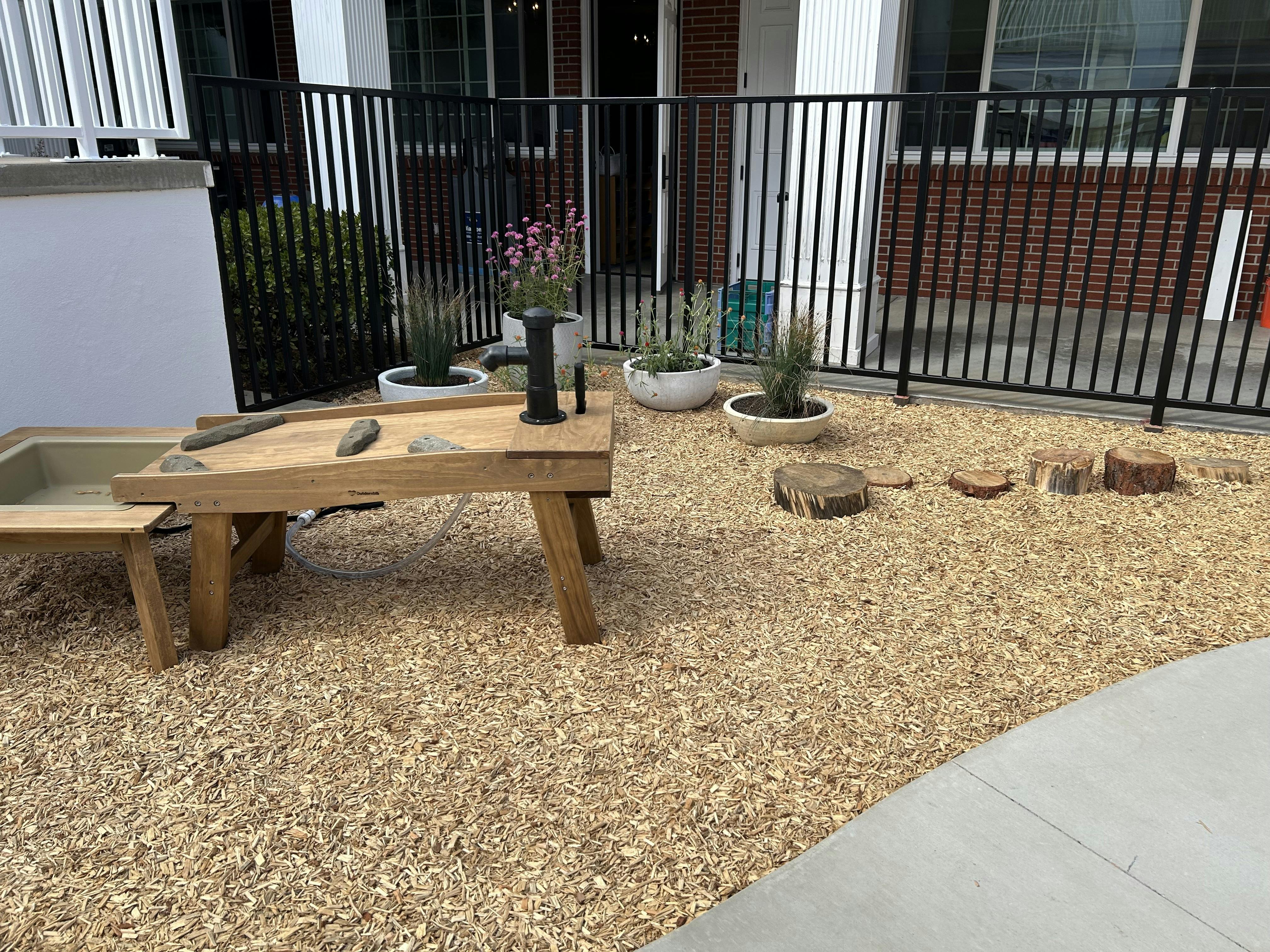 Wooden water play table with a hand pump in a playground area