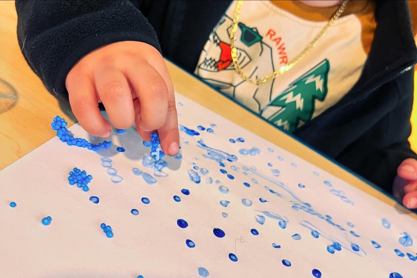 Child's hand touching blue beads on paper