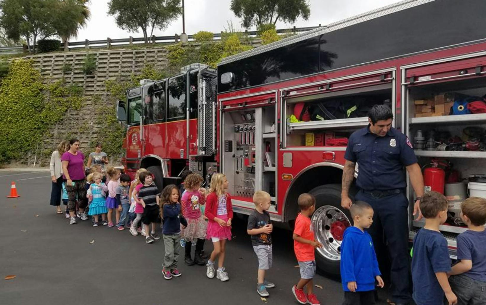 Children lining up to see a fire truck with an adult supervising