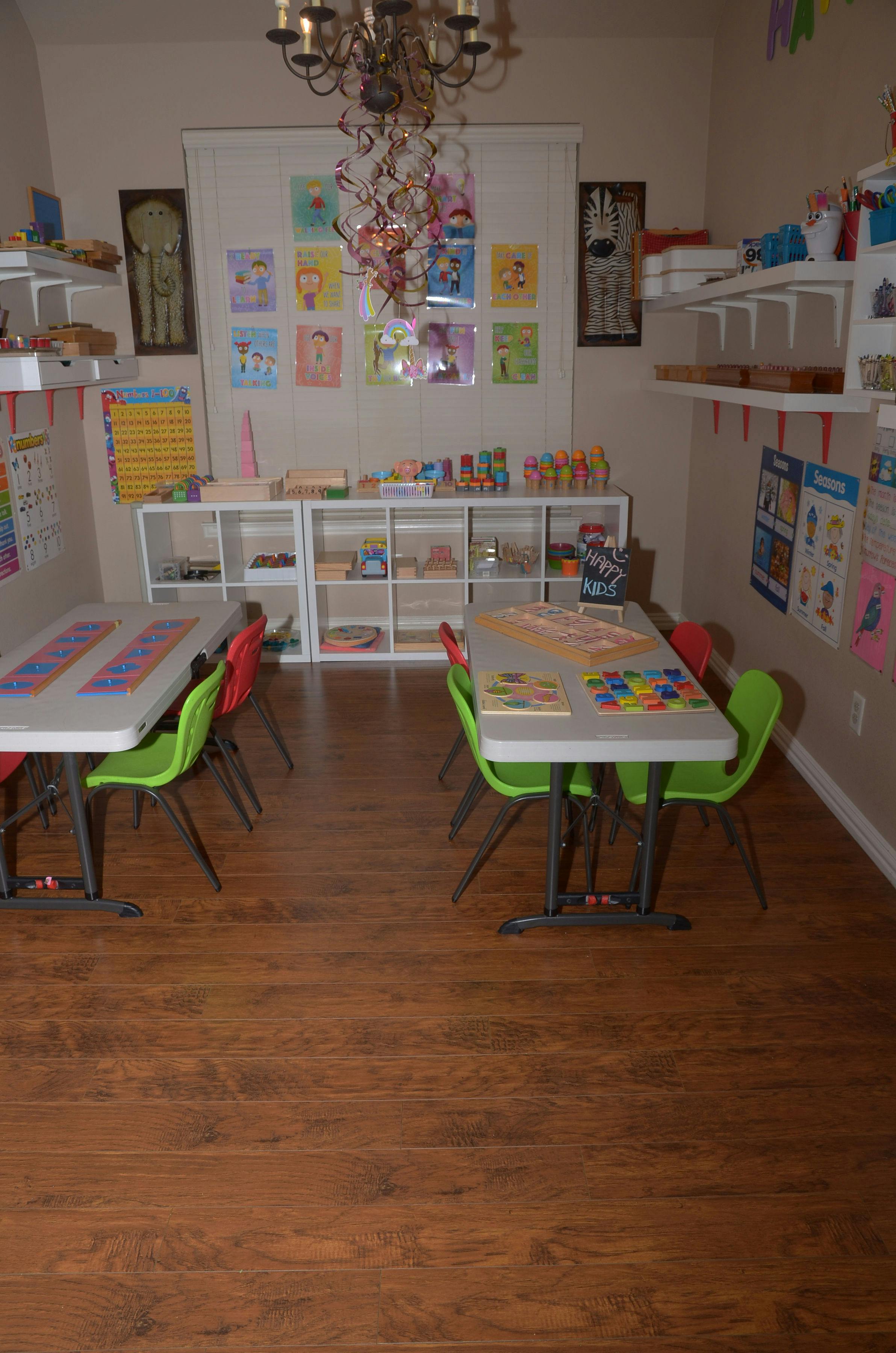 Classroom with two tables and chairs, shelves with learning materials