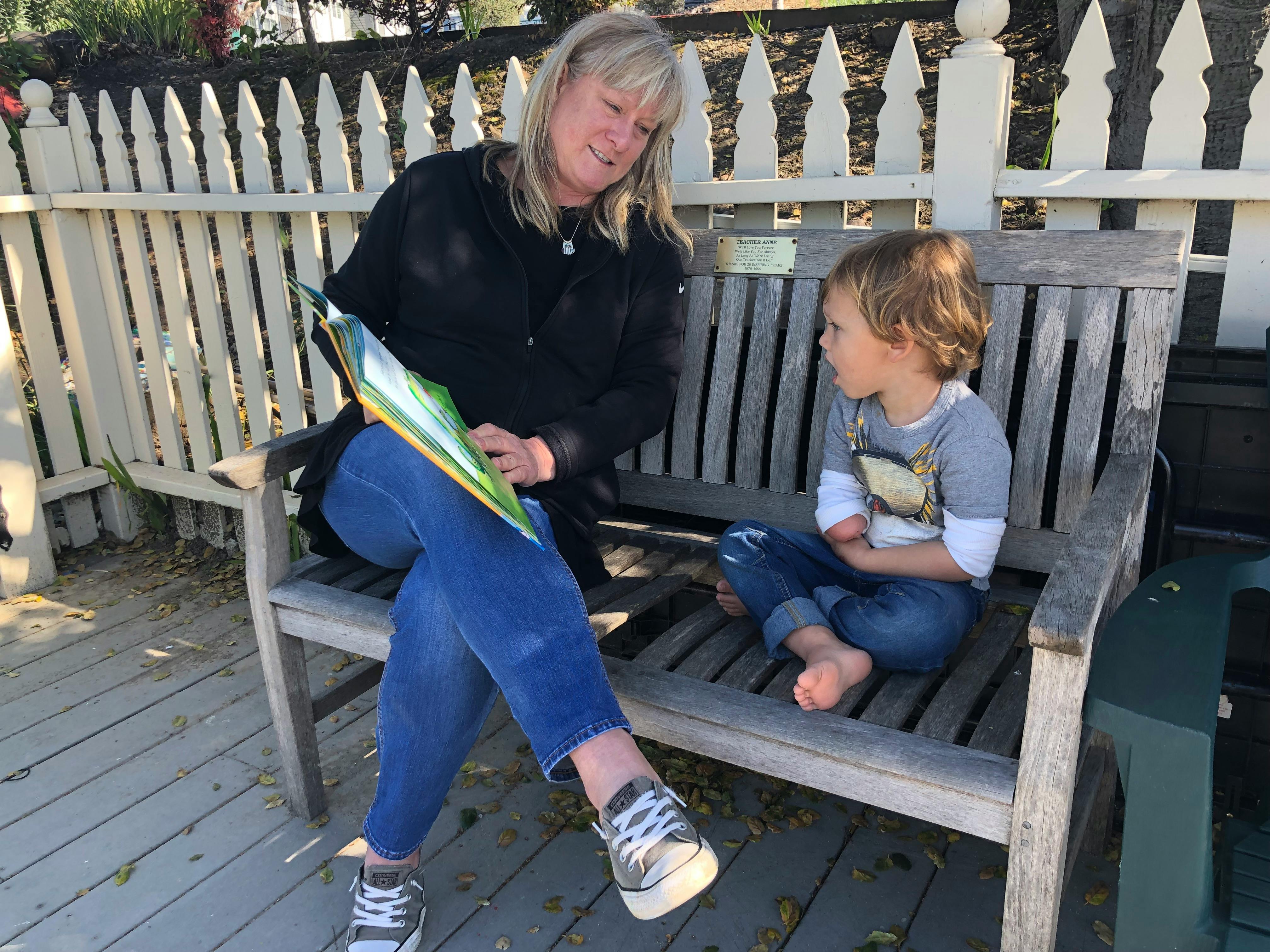 Person reading to a child on a bench
