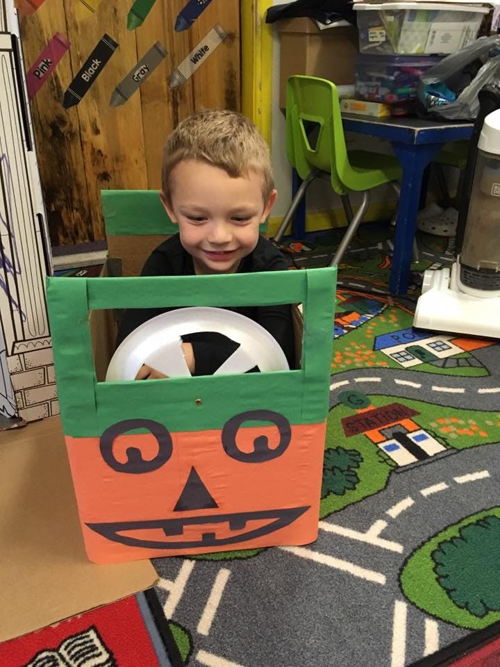 Child in a classroom looking out from a pumpkin-themed box