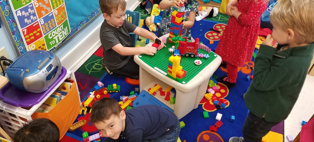 Children playing with building blocks on a colorful rug