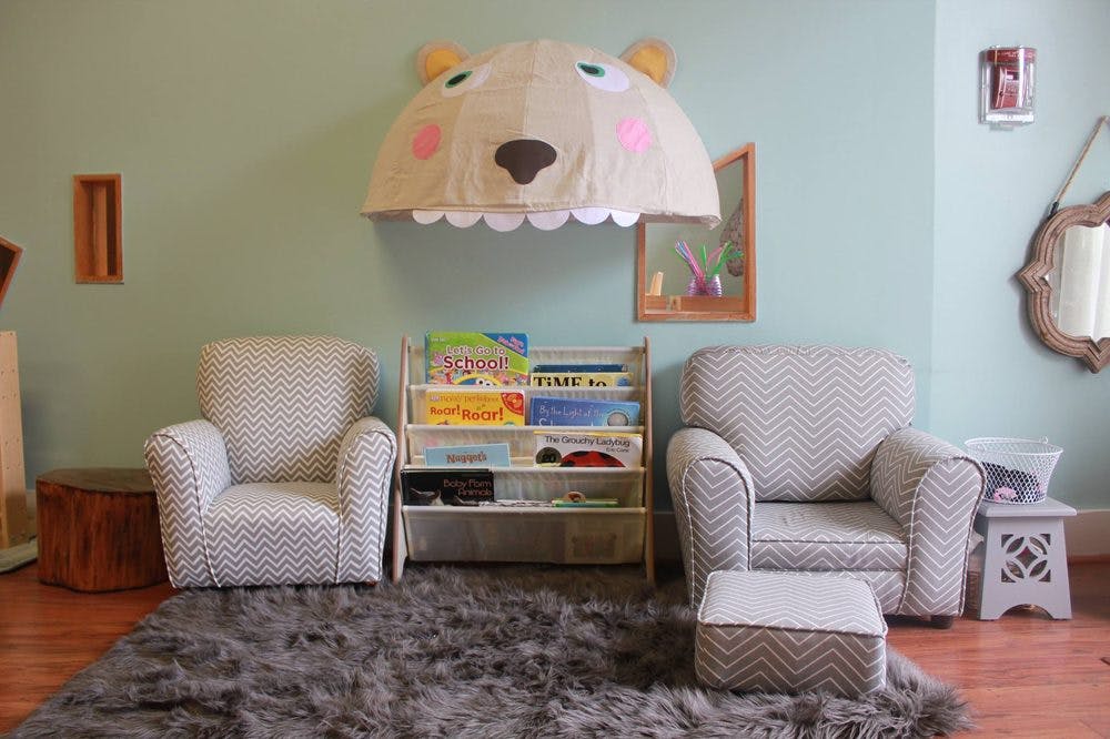 Children's room with two armchairs, a bookshelf, and a bear-shaped canopy