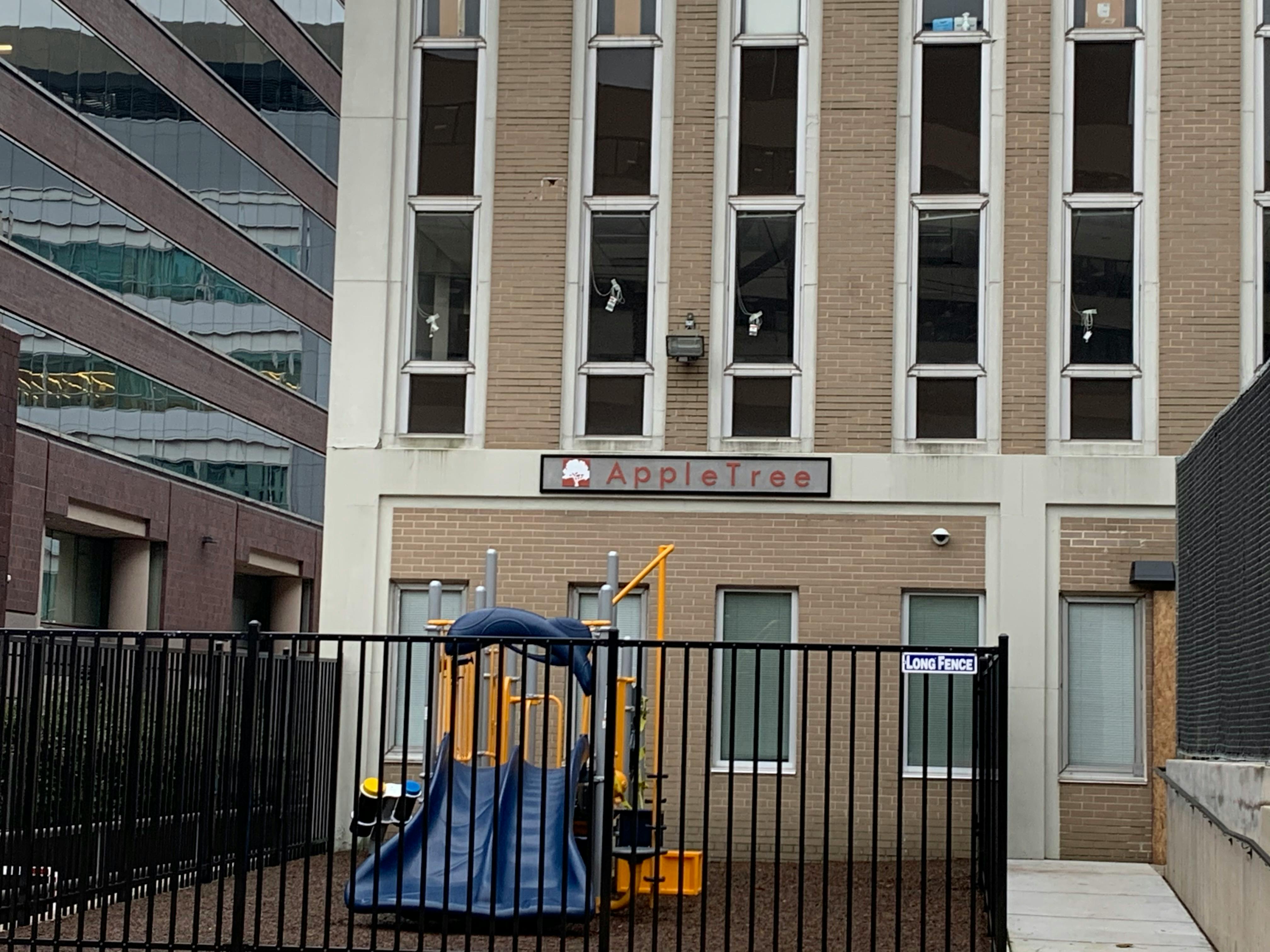 Playground with a blue slide in front of a building with an "Appletree" sign