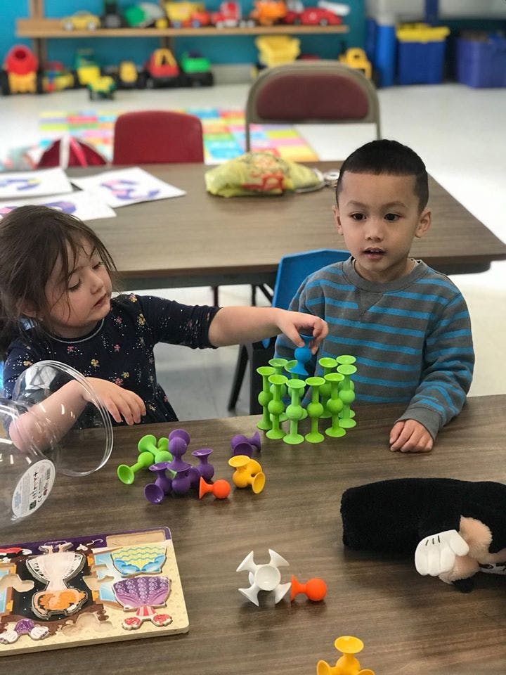 Two children playing with colorful building toys at a table