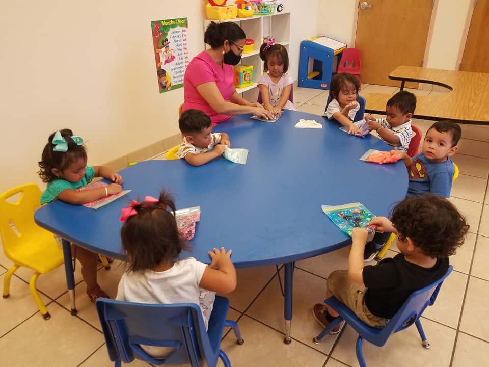 Adult and children sitting around a blue table in a classroom