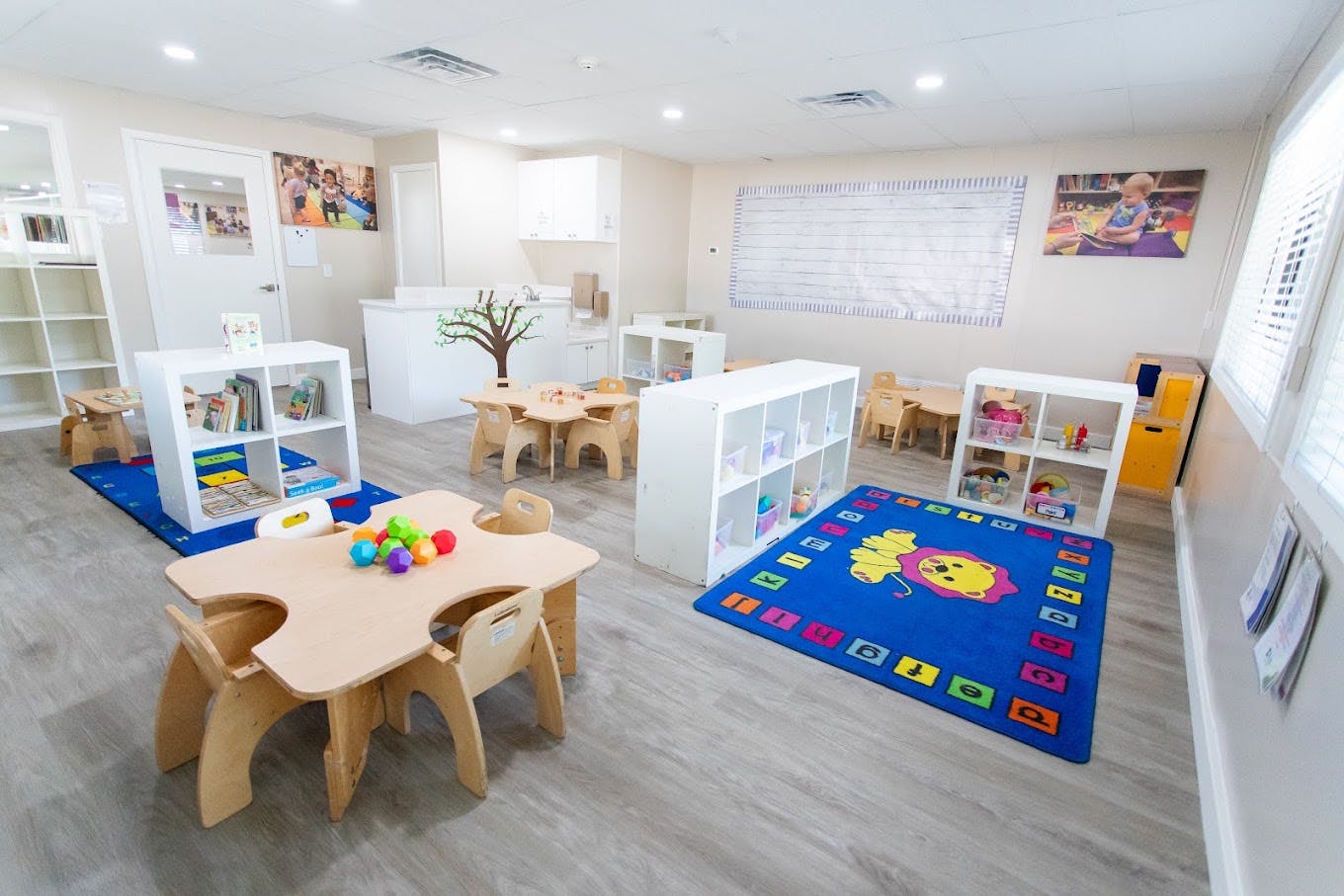 Children's classroom with small tables, chairs, and learning rugs