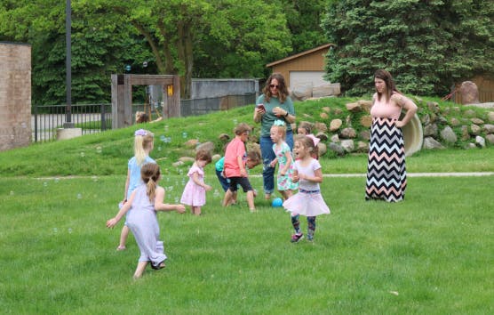 Adults and children playing outdoors on grass