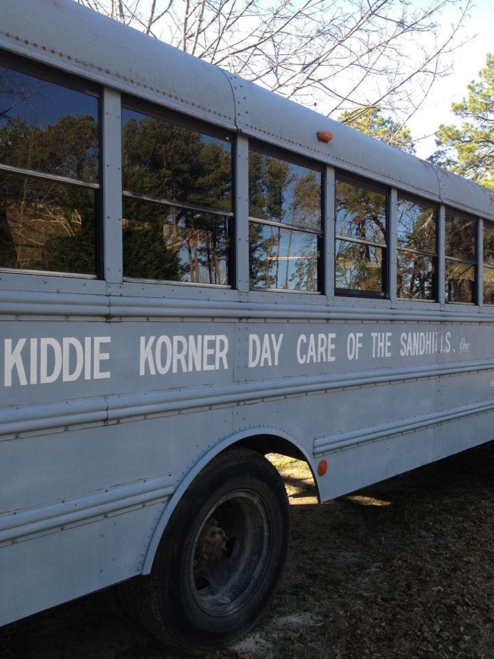 Side of a bus with "Kiddie Korner Day Care of the Sandhills" written on it