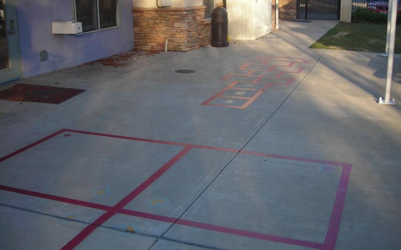 Hopscotch and other game outlines painted on a paved area next to a building