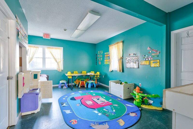 Playroom with a colorful rug, small table and chairs, and toys