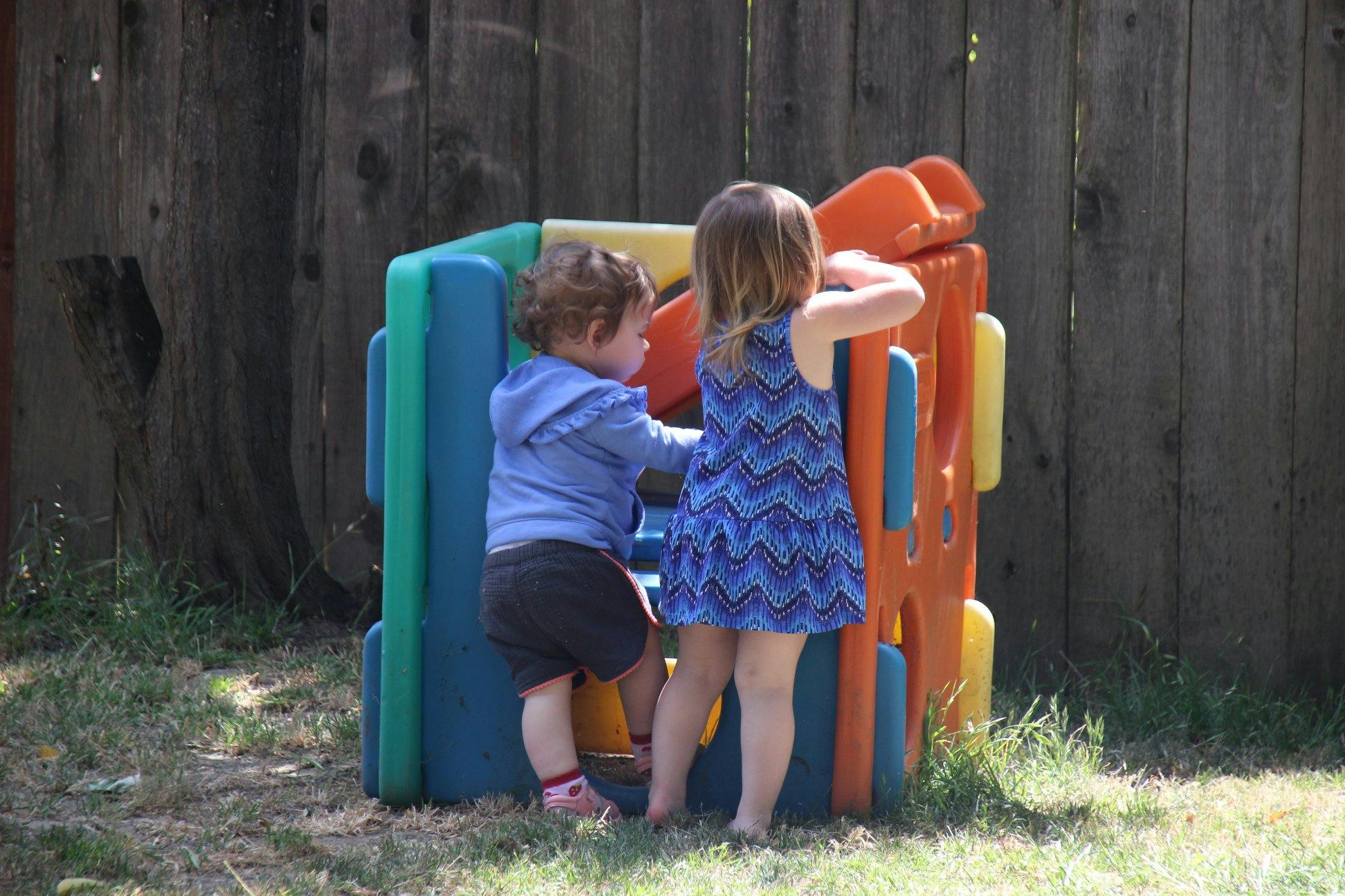 Two children playing on a colorful outdoor play structure