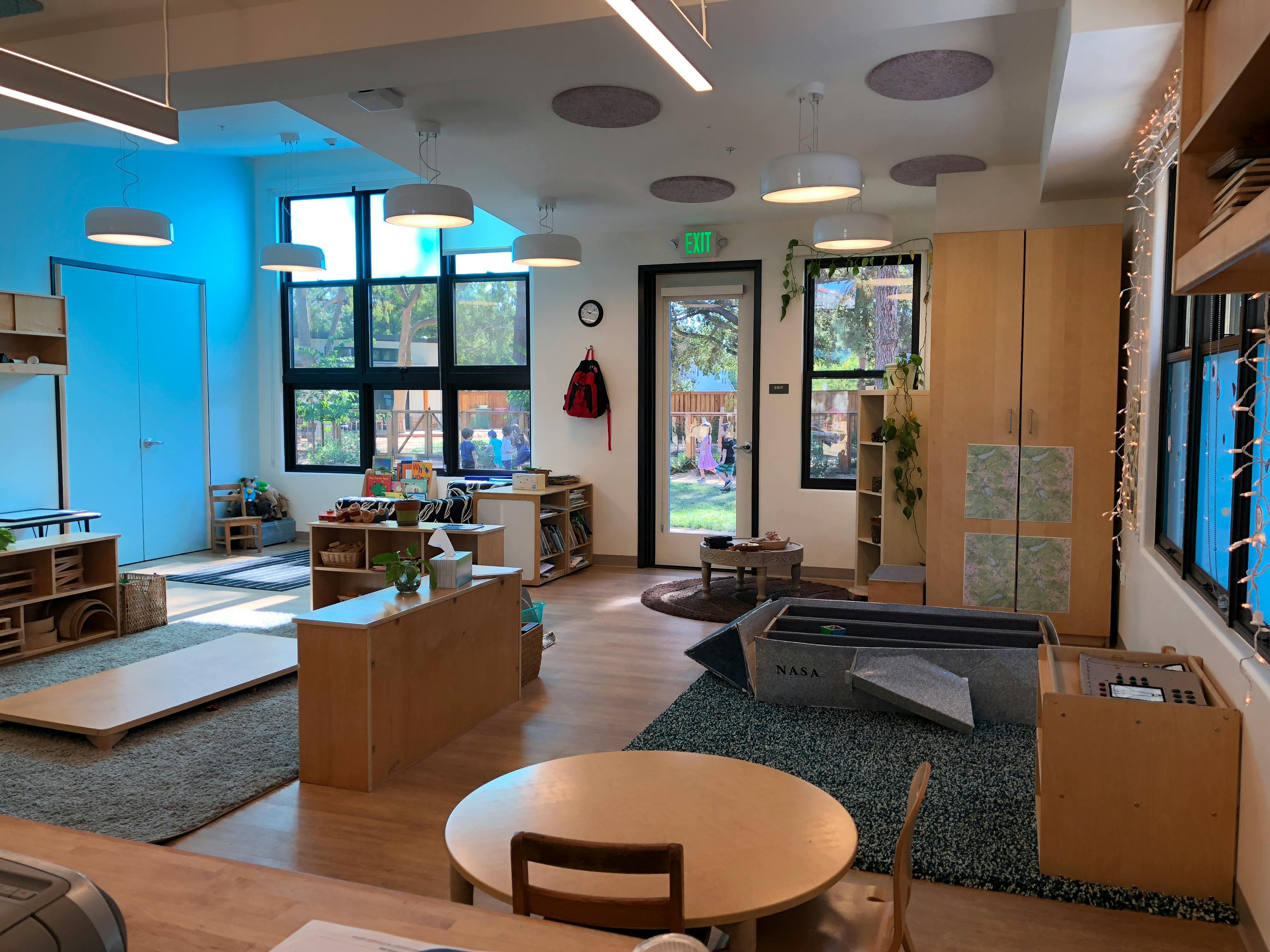 Classroom with wooden furniture, large windows, and a blue wall