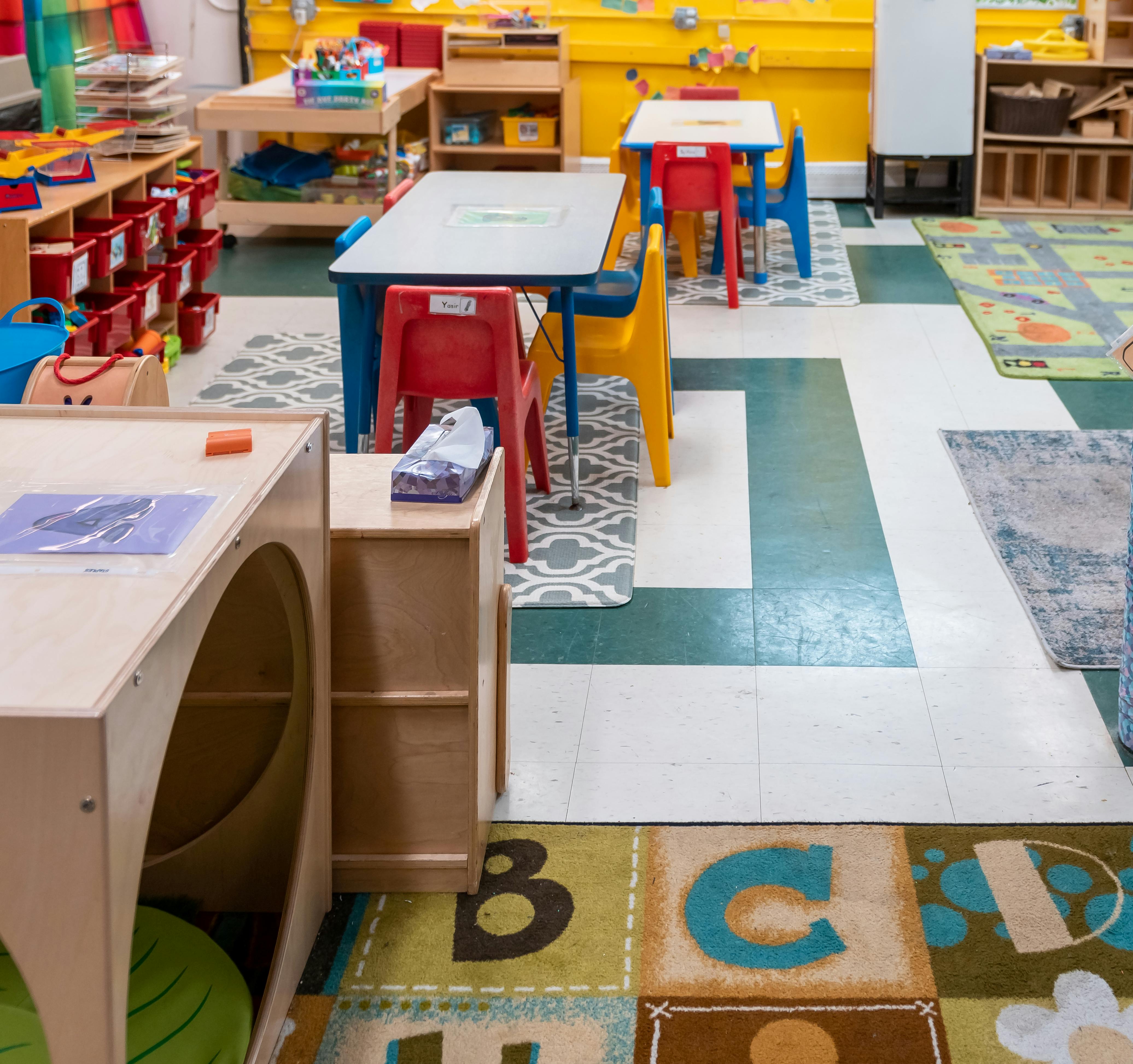 Classroom with small tables and chairs, alphabet rug
