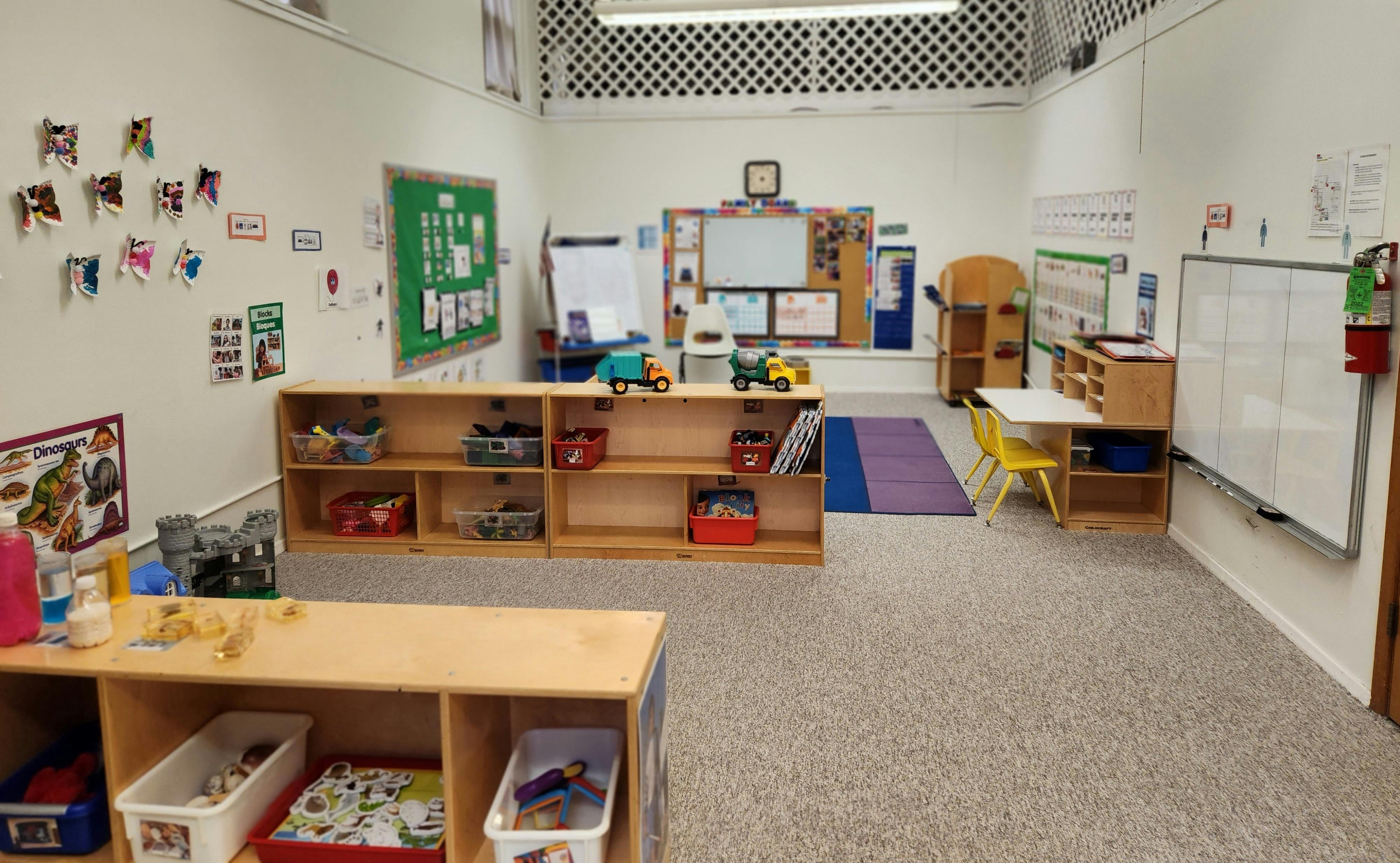 Empty classroom with shelves, tables, and whiteboards