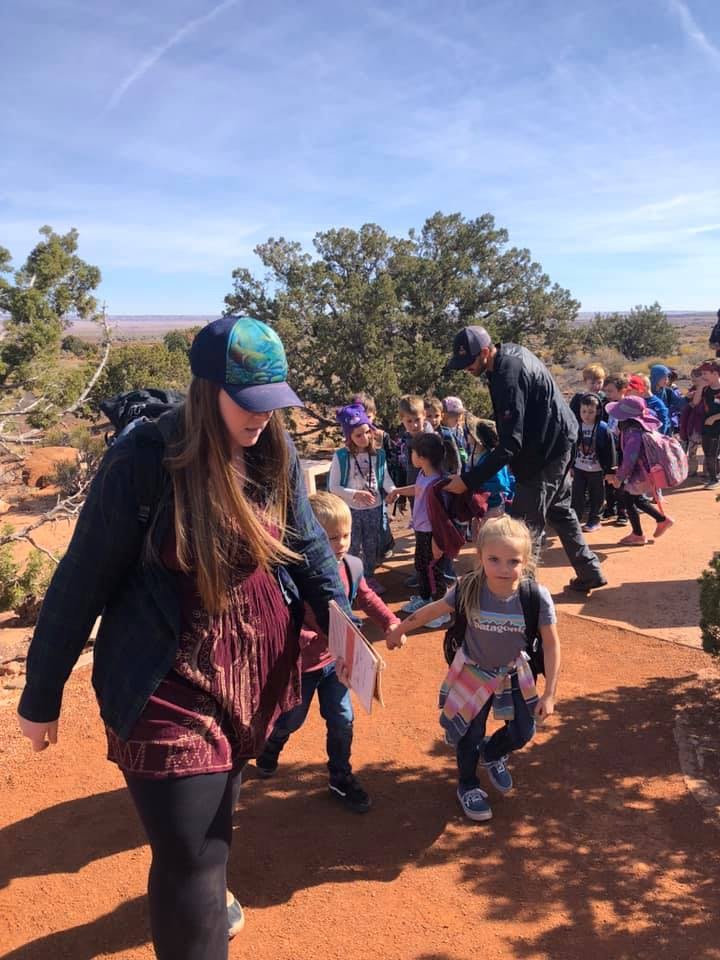 Adults and children walking on a dirt path outdoors