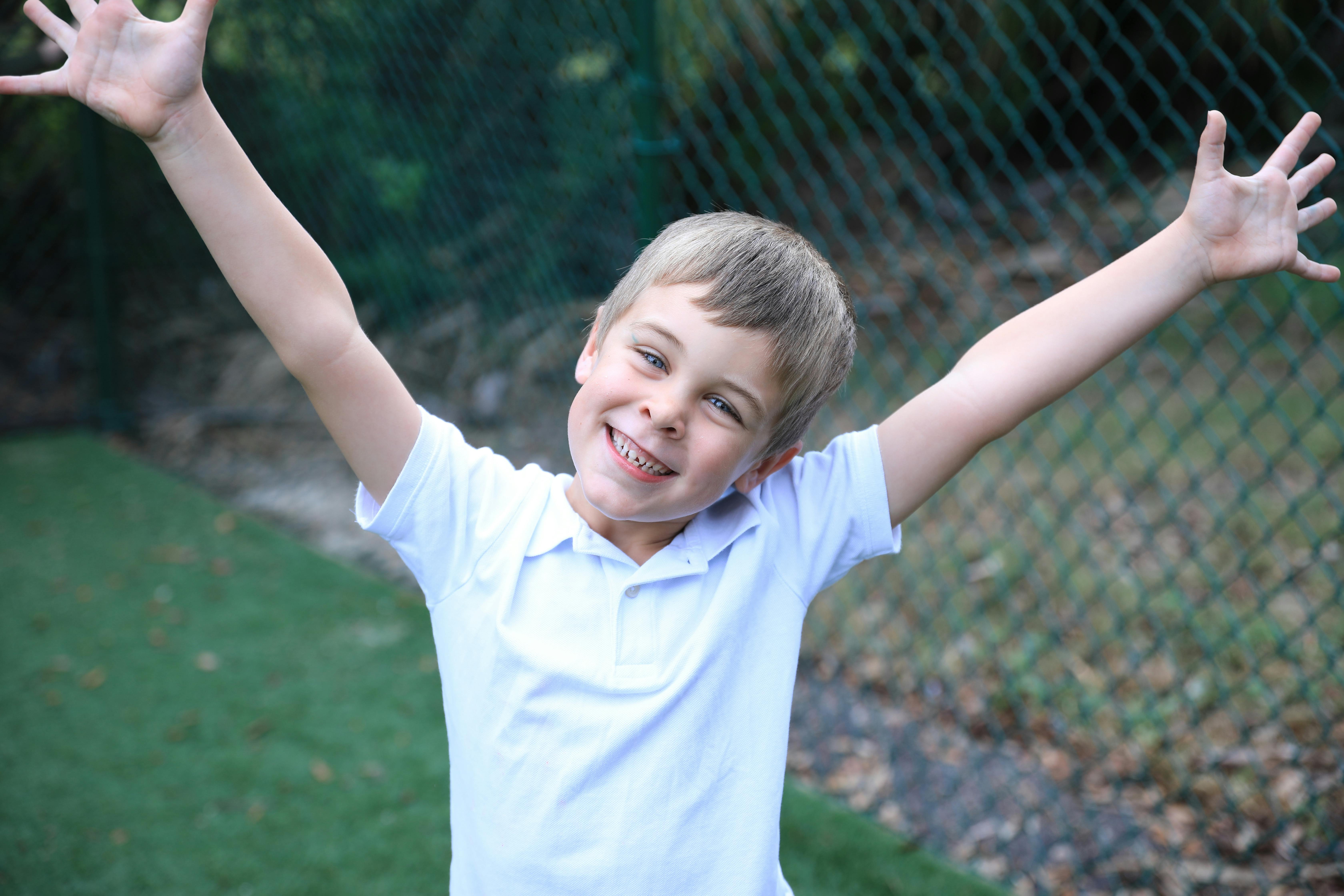 Child with arms raised and tongue out