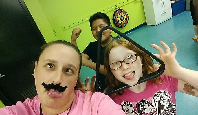 Person with fake mustache making a face with two children