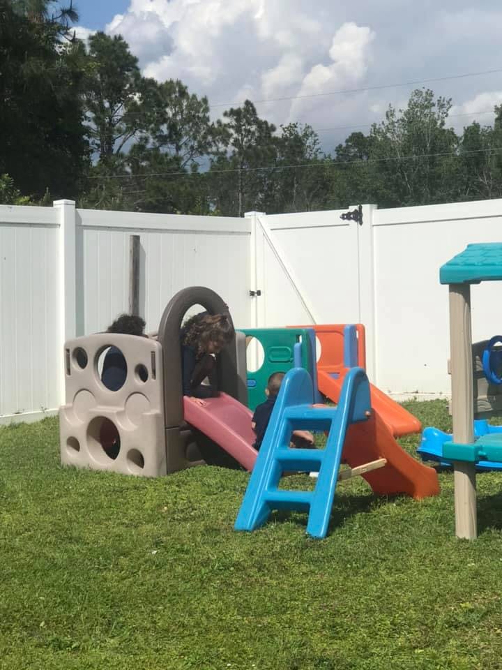 Two children playing on a colorful outdoor playset with slides