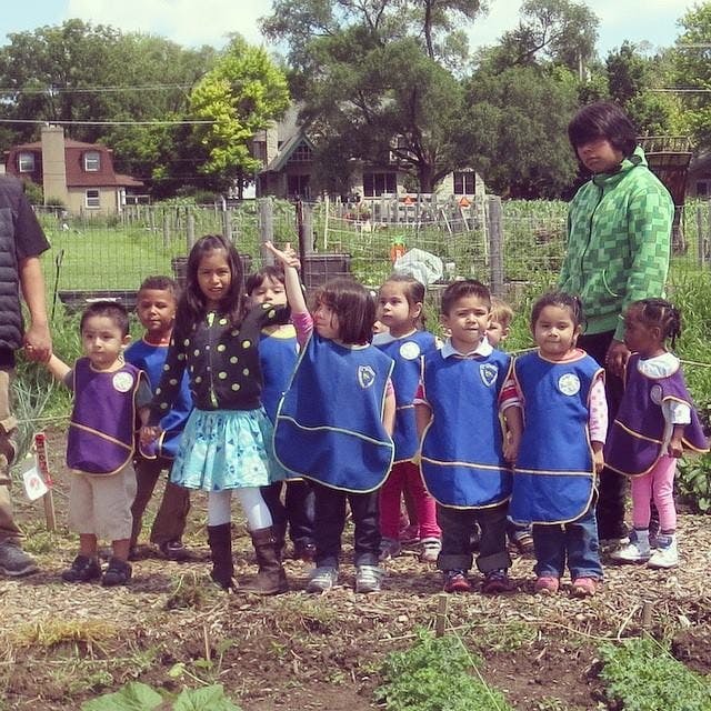 Adult and group of children in smocks standing in a garden