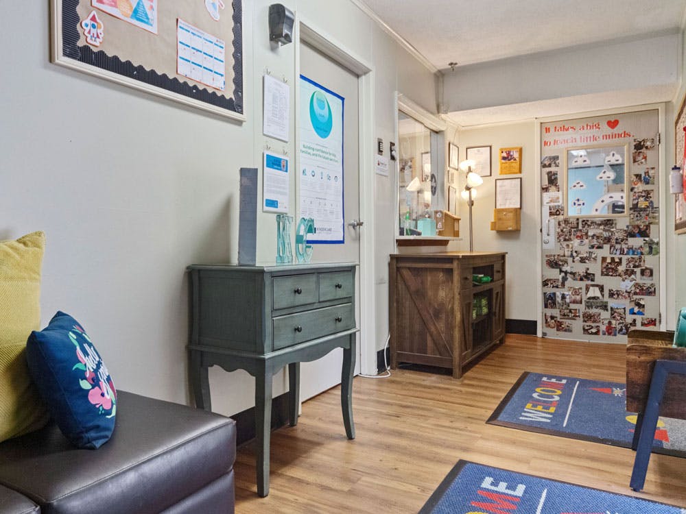 An indoor room with a bulletin board, small cabinet, and a door covered in photos