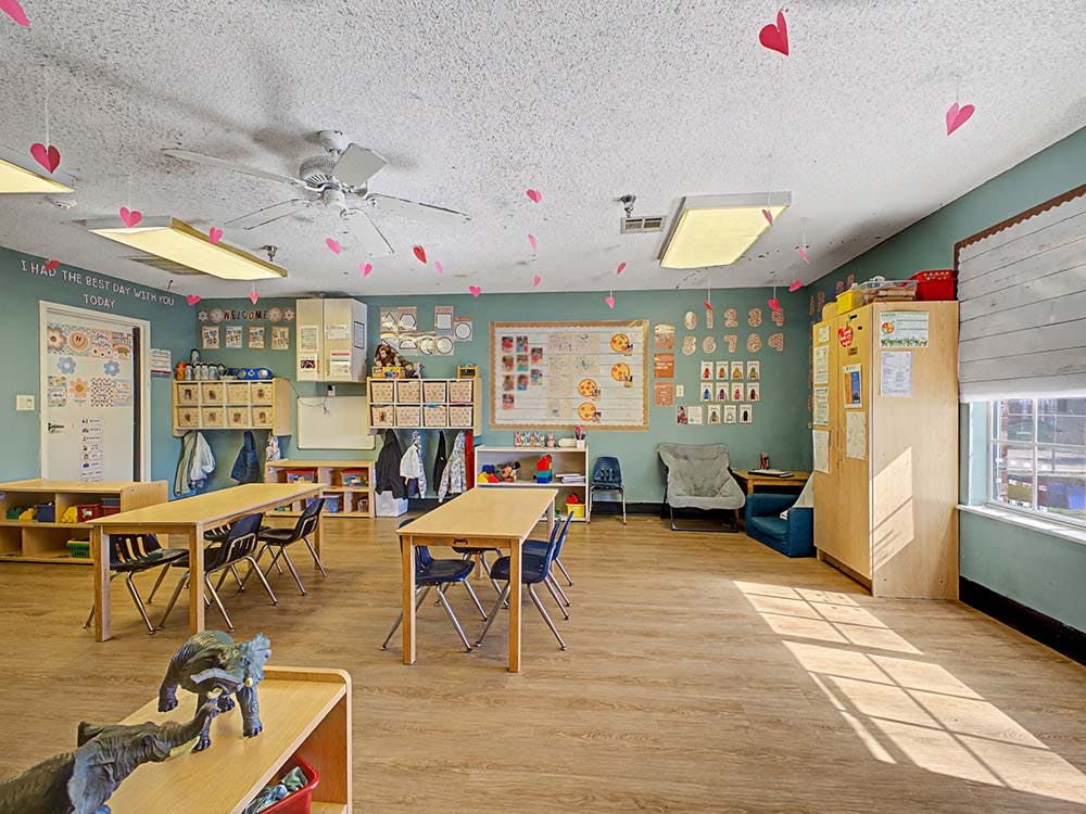 Classroom with tables, chairs, decorations, and a bulletin board
