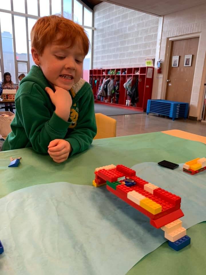 Child looking at a Lego creation on a table