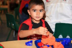 Child playing with orange modeling clay