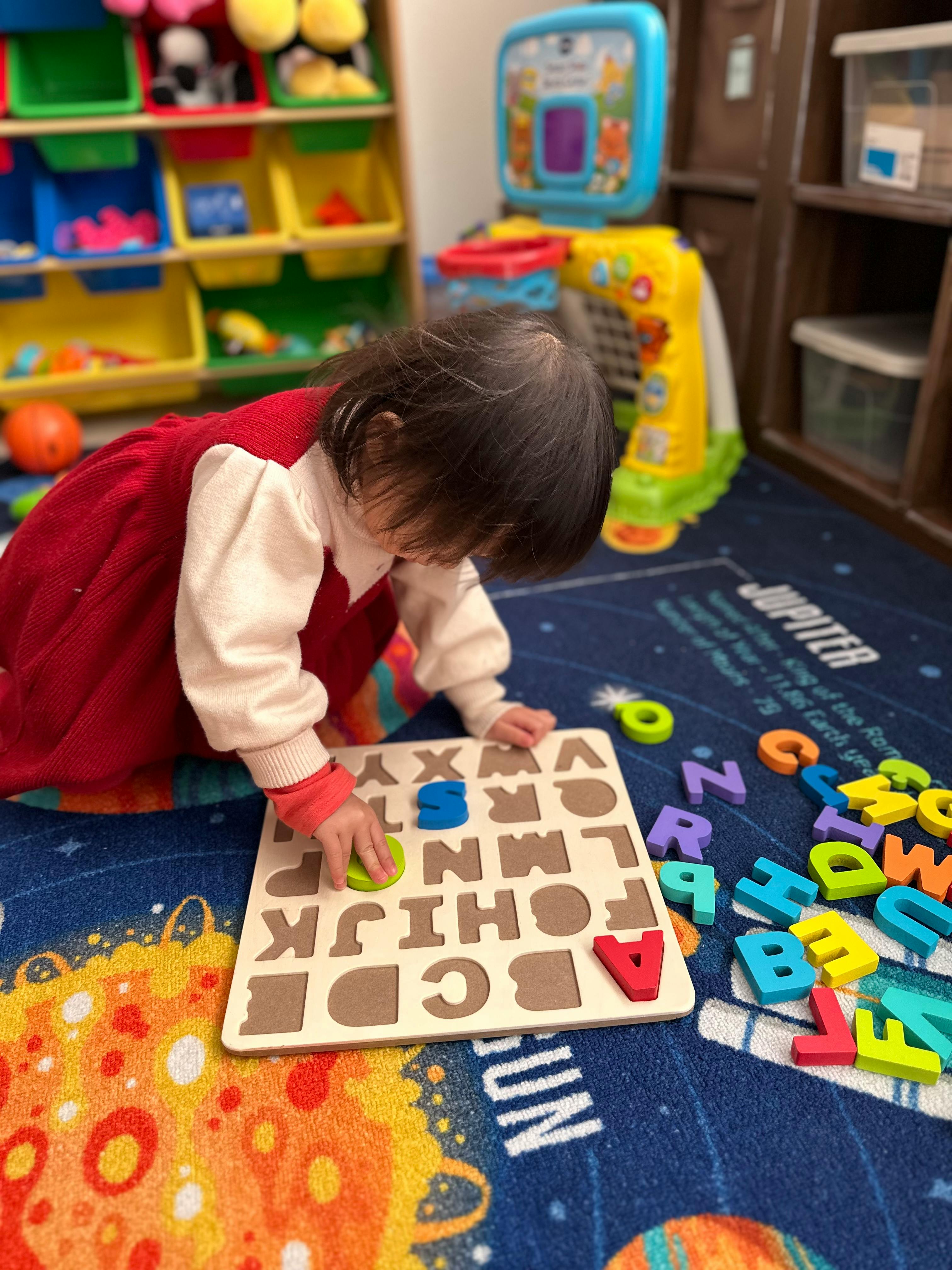 Child playing with an alphabet puzzle on a rug
